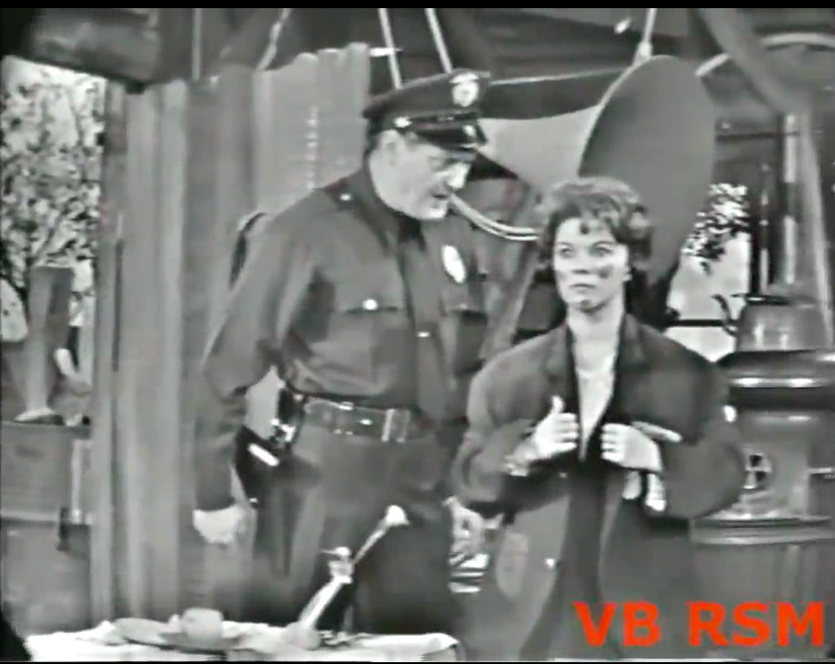 Officer Ray Kellogg confronts the missing socialite Shirley Temple in Freddie's shack