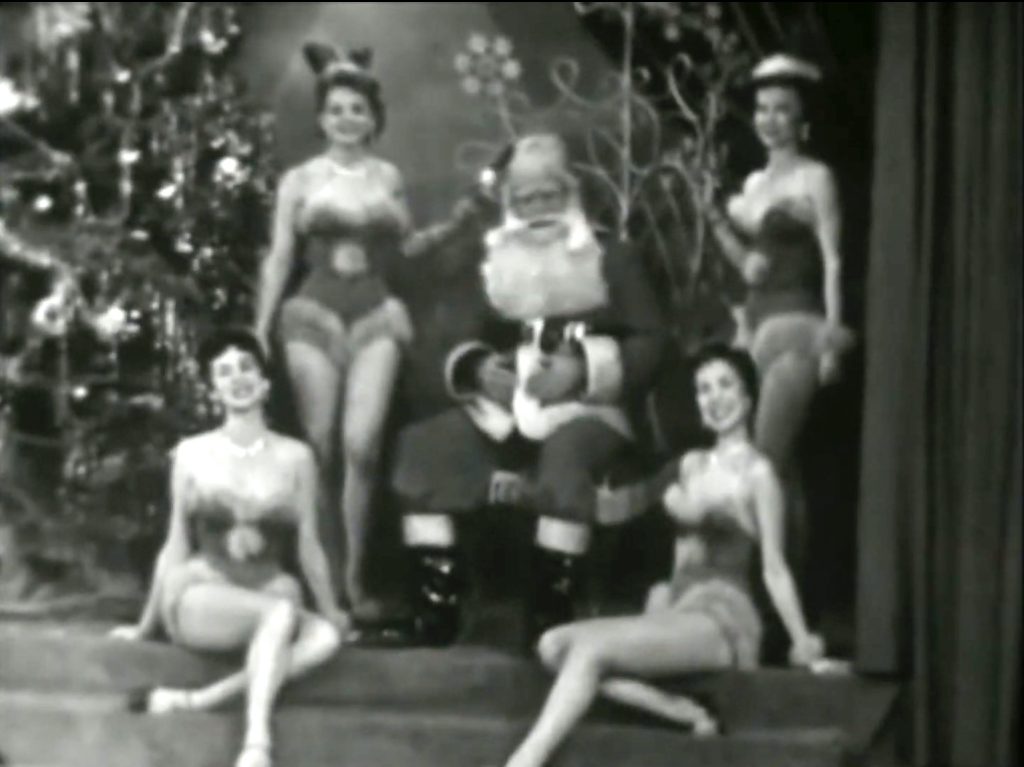 Santa Claus surrounded by dancers in the 'Santa Claus is Coming to Town' (opening musical number)
