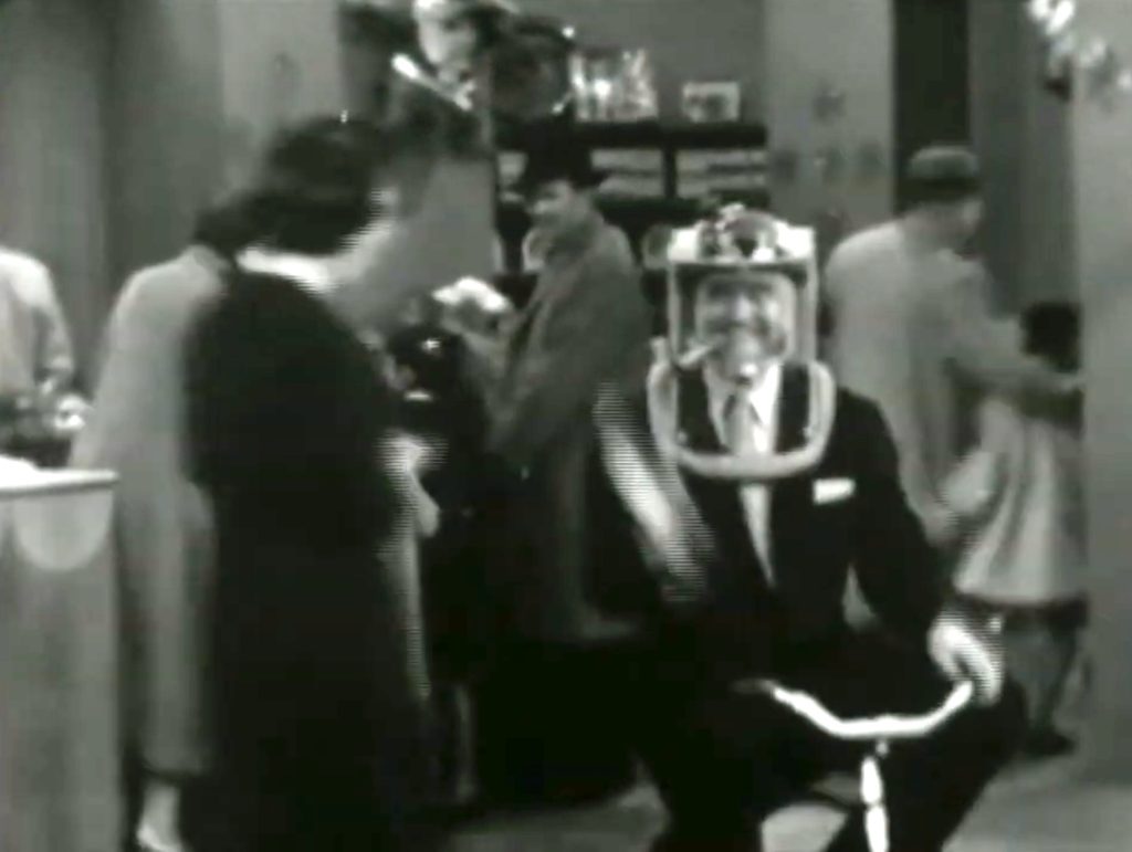Red Skelton, a kid at heart, riding a tricycle and wearing a space helmet at the department store